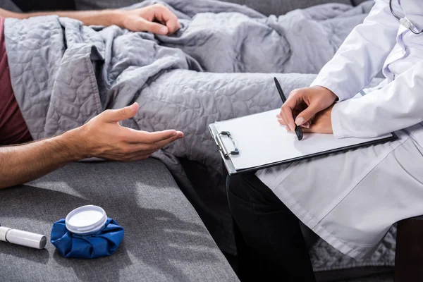 Cropped shot of doctor with clipboard sitting near patient with clipboard — Stock Photo