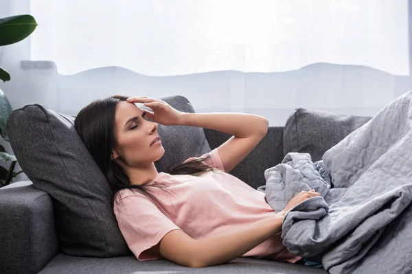 Jeune femme souffrant de maux de tête alors qu'elle était allongée sur le canapé — Photo de stock