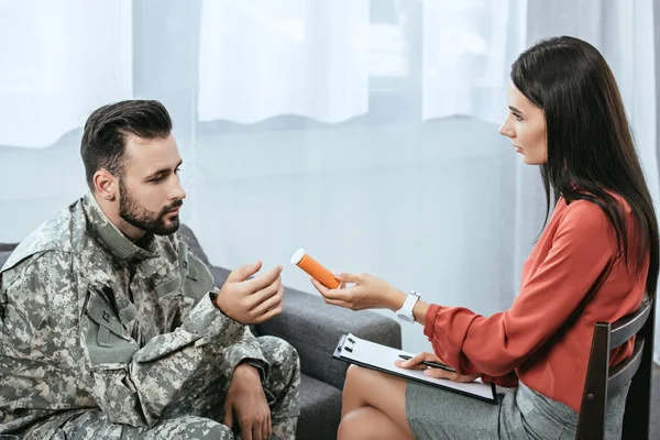 Psiquiatra dando recipiente de pílulas para soldado durante sessão de terapia — Fotografia de Stock