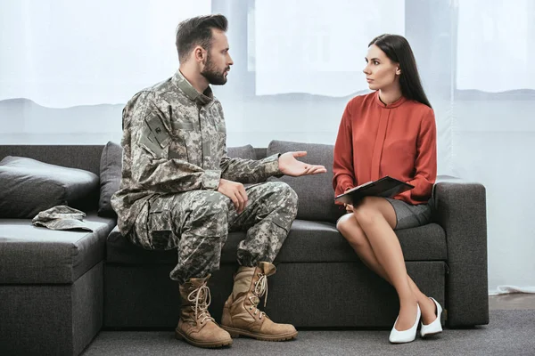 Soldado en uniforme militar con ptsd hablando con psiquiatra en sesión de terapia - foto de stock