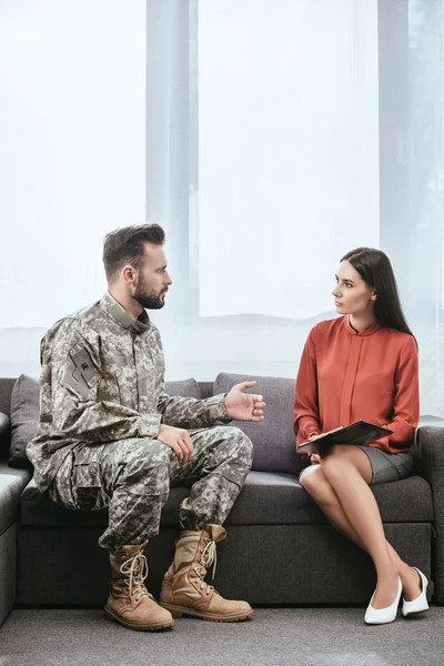 Soldado enojado con ptsd hablando con psiquiatra en sesión de terapia - foto de stock