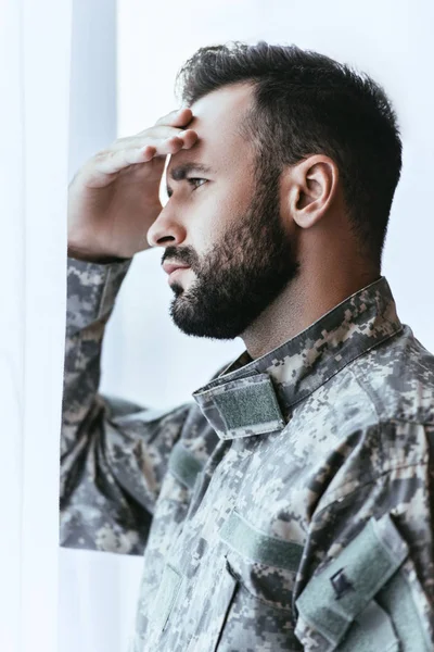 Depressed army man in military uniform with post-traumatic stress disorder touching his head and looking away — Stock Photo