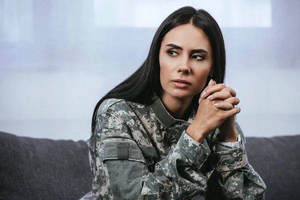 Крупним планом портрет вдумливої жінки-солдата у військовій формі з ptsd сидячи на дивані і дивлячись — стокове фото