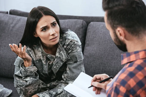 Depressed female soldier with ptsd talking to psychiatrist at therapy session — Stock Photo