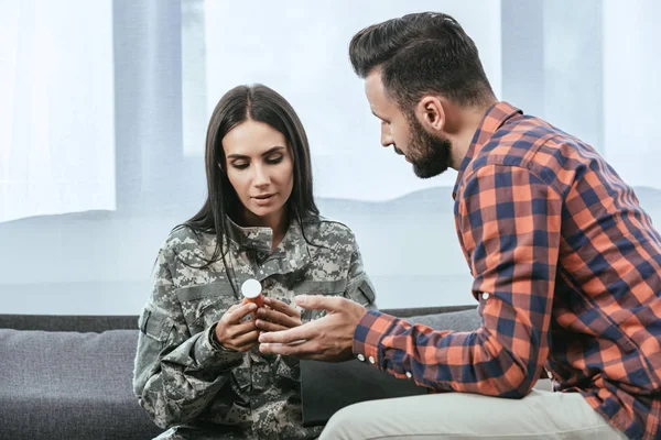 Psiquiatra dando frasco de píldoras a soldado femenino durante la terapia - foto de stock