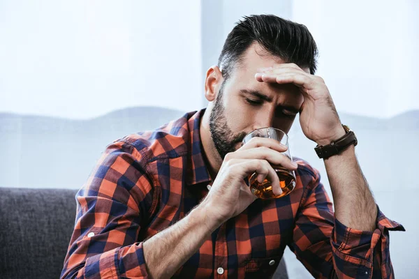 Retrato de cerca del joven deprimido bebiendo whisky - foto de stock