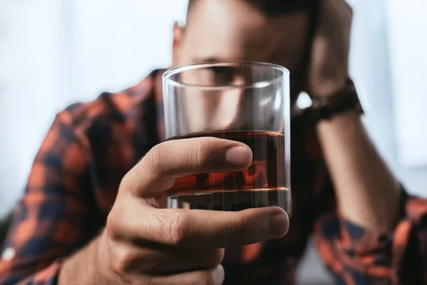 Primo piano di un uomo depresso che tiene un bicchiere di whisky — Foto stock