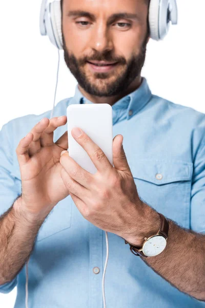 Hombre barbudo escuchando música y usando teléfono inteligente aislado en blanco - foto de stock