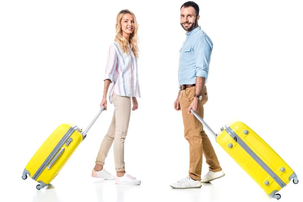 Feliz pareja con bolsas de viaje amarillas aisladas en blanco - foto de stock