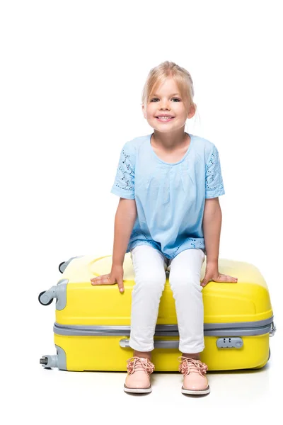 Criança sentada na bagagem amarela isolada no branco — Fotografia de Stock