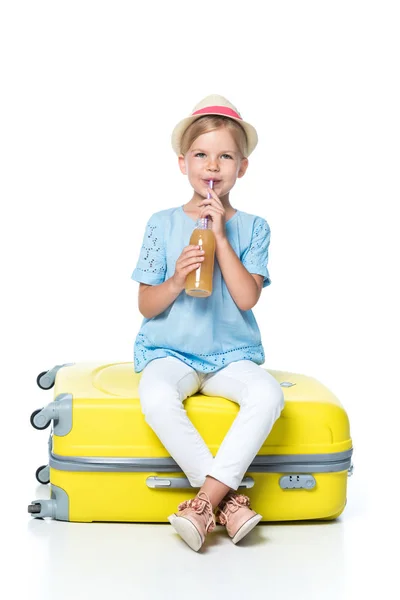 Niño con bebida sentado en el equipaje amarillo aislado en blanco - foto de stock