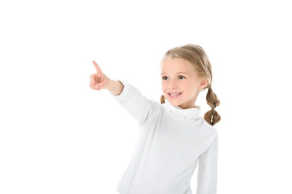 Очаровательный улыбающийся ребенок с косичками, показывающий что-то, изолированное на белом — стоковое фото