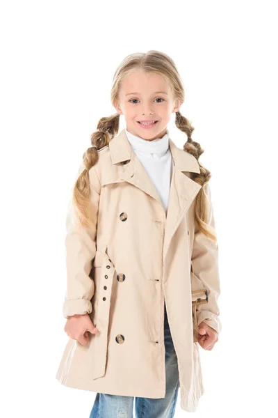 Чарівна усміхнена дитина позує в бежевому осінньому пальто, ізольована на білому — стокове фото
