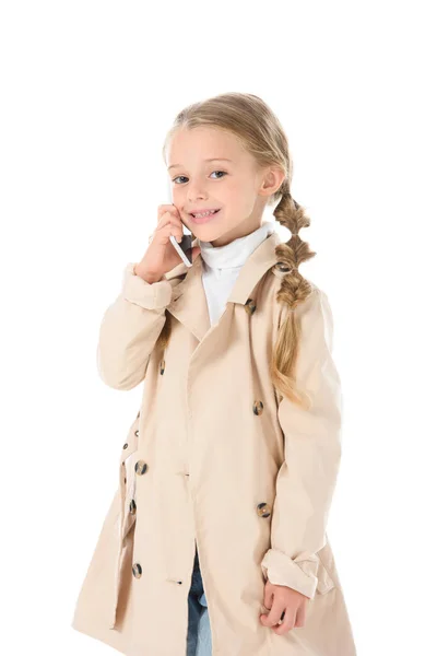 Adorable enfant en manteau beige automne parlant sur smartphone, isolé sur blanc — Photo de stock