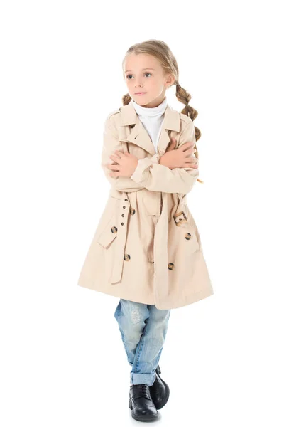 Стильный ребенок позирует в осеннем пальто со скрещенными руками, изолированный на белом — стоковое фото