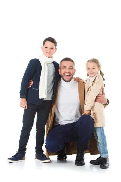 Улыбающийся отец обнимает стильных детей в осеннем наряде, изолированных на белом — стоковое фото