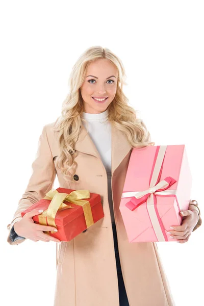 Приваблива усміхнена жінка в бежевому осінньому пальто тримає подарунки, ізольована на білому — стокове фото