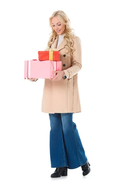 Mujer sonriente en abrigo beige sosteniendo cajas de regalo, aislado en blanco - foto de stock