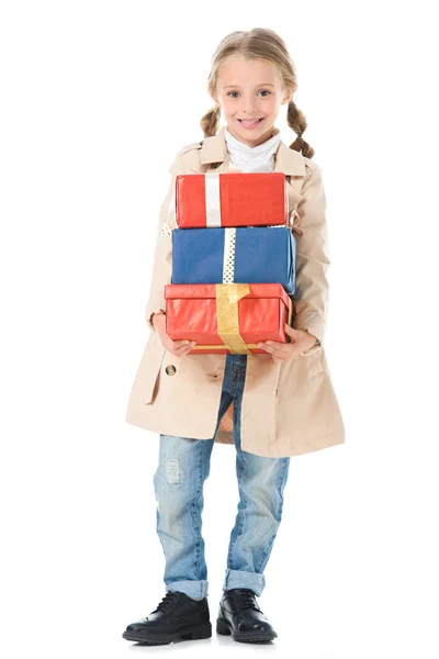Adorable enfant en manteau beige tenant des boîtes-cadeaux, isolé sur blanc — Photo de stock