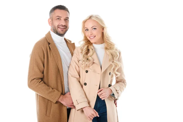 Belo casal sorridente posando em casacos bege, isolado em branco — Fotografia de Stock