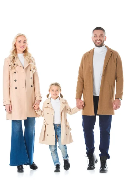 Famiglia che si tiene per mano con la figlia e posa in cappotti autunno beige, isolato su bianco — Foto stock