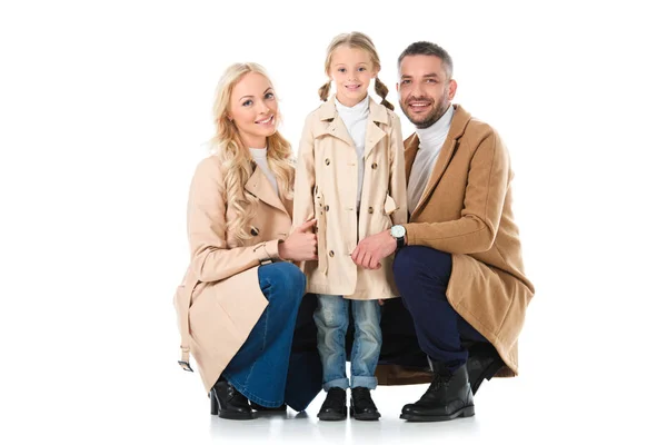 Hermosos padres con adorable hija en abrigos beige, aislados en blanco - foto de stock