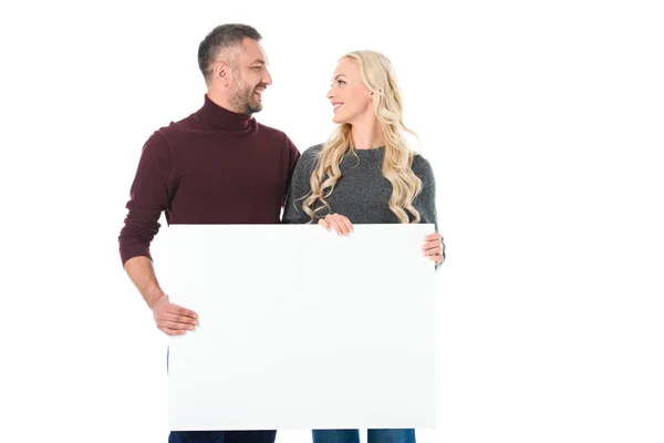 Couple en tenue d'automne tenant une pancarte vide et se regardant, isolé sur blanc — Photo de stock