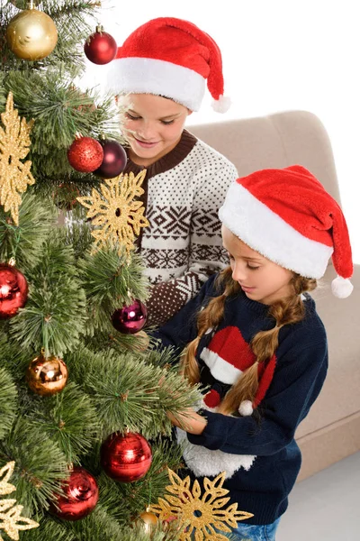 Hermano y hermana en el árbol de Navidad de la decoración del sombrero de santa, aislado en blanco - foto de stock