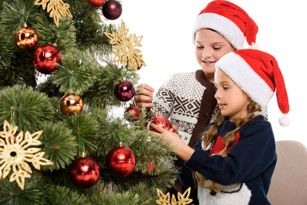 Kids in santa hat decorating christmas tree with balls — Stock Photo