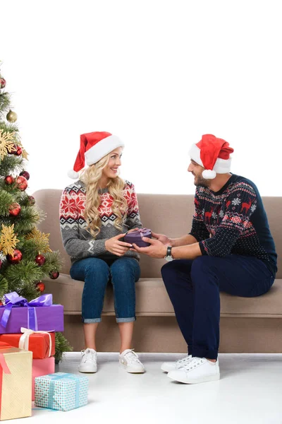 Happy couple in santa hats gifting presents near christmas tree, isolated on white — Stock Photo