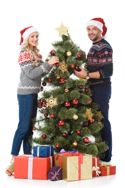 Hermosa pareja decorando árbol de Navidad con cajas de regalo, aislado en blanco - foto de stock