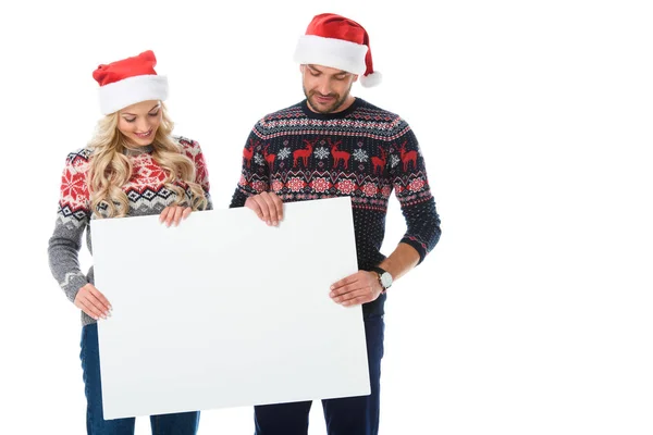 Coppia in maglioni di Natale e cappelli di Babbo Natale in possesso di pensione vuota, isolato su bianco — Foto stock