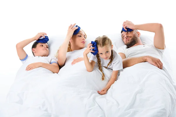 Familia enferma perturbada con la temperatura sosteniendo bolsas de hielo en las cabezas, aislado en blanco - foto de stock