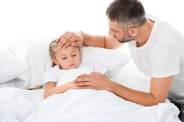 Parent touching forehead of sick daughter with temperature lying in bed, isolated on white — Stock Photo