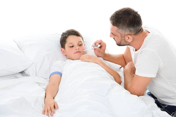 Батько вимірює температуру тіла хворого сина, ізольований на білому — стокове фото