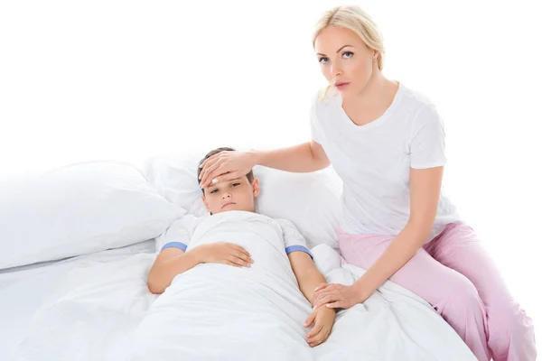 Mother touching forehead of sick son with temperature, isolated on white — Stock Photo