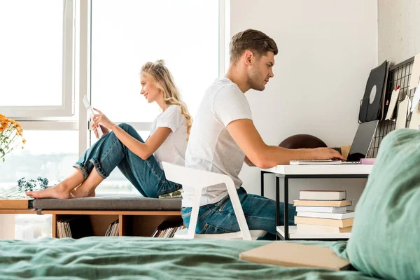 Side view of young couple using digital devices at home — Stock Photo
