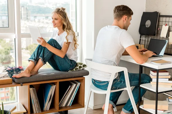 Young couple using digital devices at home — Stock Photo