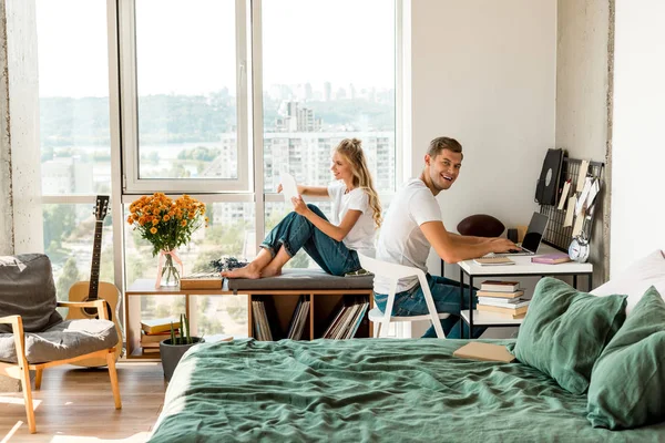 Vue latérale du jeune couple utilisant des appareils numériques à la maison — Photo de stock