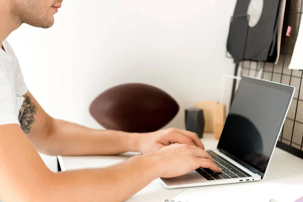 Vista parcial del freelancer utilizando el ordenador portátil en la mesa en la oficina en casa - foto de stock