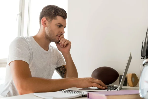 Vue latérale de l'homme concentré utilisant un ordinateur portable à la table au bureau à la maison — Photo de stock