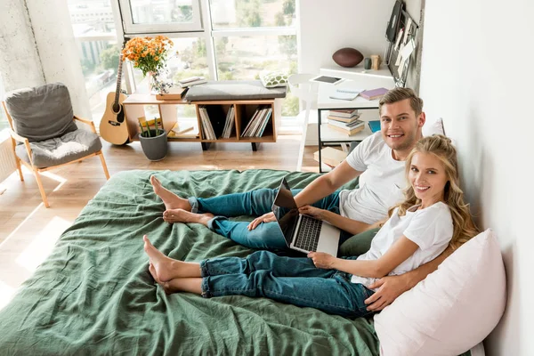 Висока кут зору молода пара з цифрових ноутбук, лежачи на ліжку у себе вдома — стокове фото