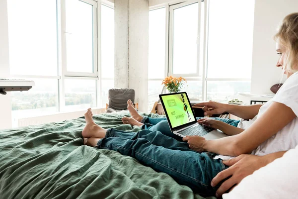 Vue partielle du couple avec ordinateur portable numérique avec le meilleur lettrage shopping à l'écran reposant sur le lit à la maison — Photo de stock