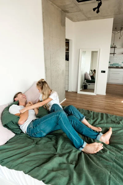 Happy young couple resting on bed together at home — Stock Photo