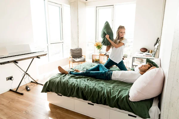 Jovem casal apaixonado ter travesseiro luta na cama em casa — Fotografia de Stock