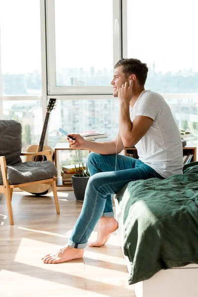 Side view of man in earphones listening music at home — Stock Photo