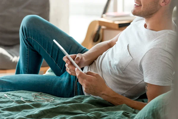 Tiro cortado de homem com tablet deitado na cama em casa — Fotografia de Stock