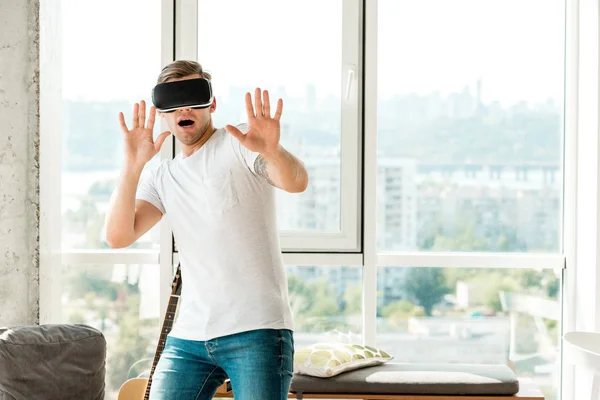 Scared young man in vr headset at home — Stock Photo