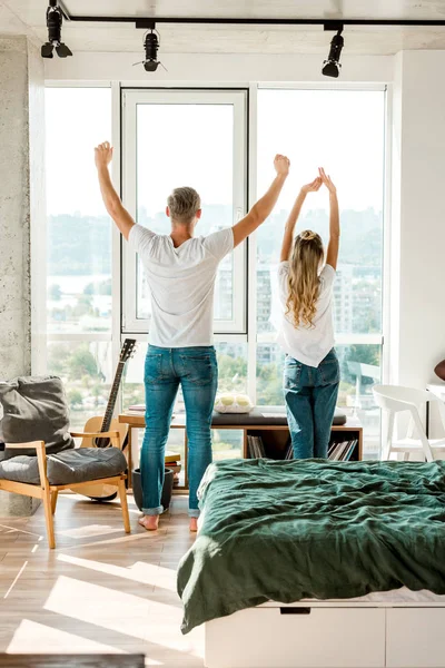 Back view of young couple stretching while standing at window — Stock Photo