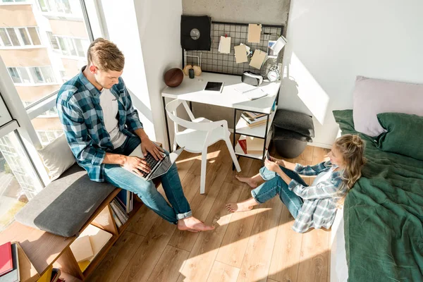 Visão de alto ângulo do casal usando dispositivos digitais em casa — Fotografia de Stock